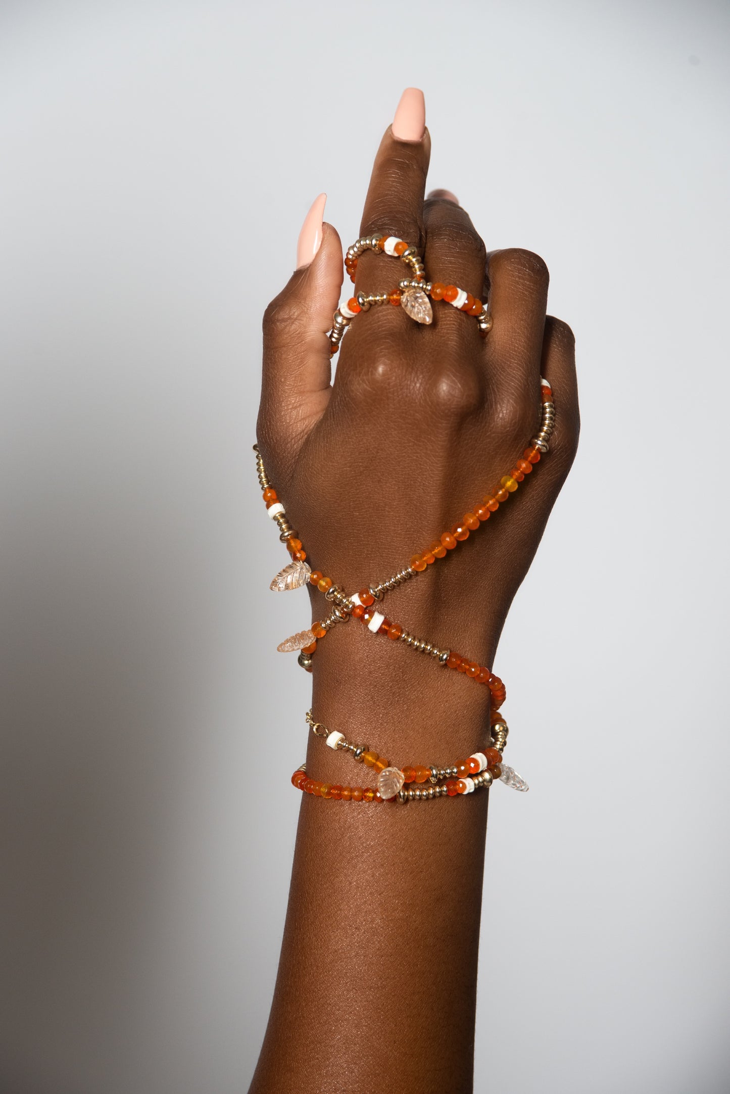 A woman's hand holding an Awaken bracelet from Ilium Wing, invoking the playful energy of the Sacral Chakra.